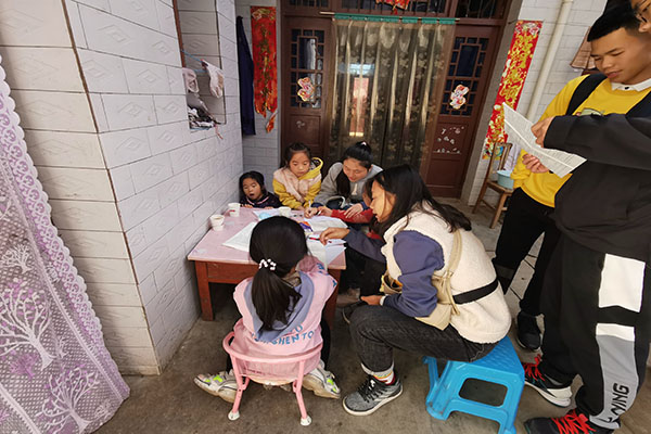 b018405f110f420b9a4c92c659c9f9ff.jpg 志愿者老师们给孩子们讲解题目.jpg